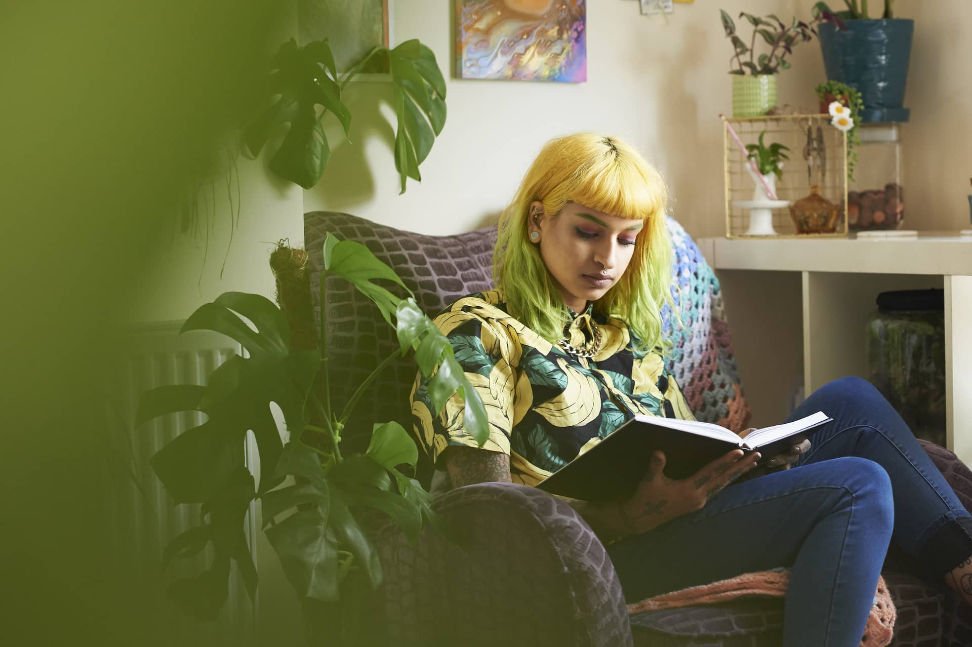 woman reading on couch sin room full of plants