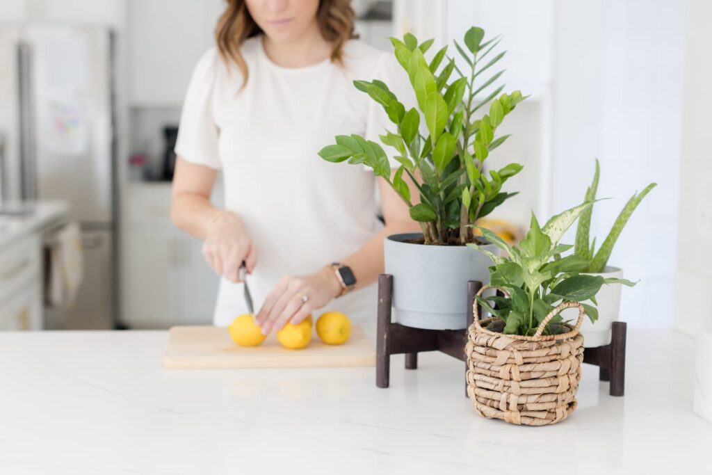 woman cutting fruit in kitchen near plants